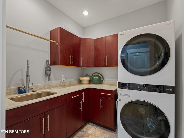 washroom featuring cabinets, stacked washing maching and dryer, and sink