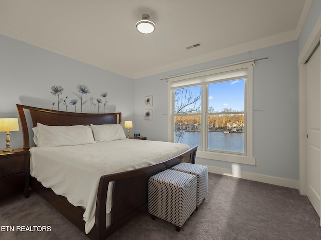 bedroom with dark carpet, ornamental molding, and a water view