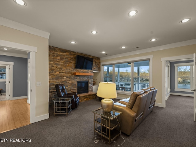 living room featuring crown molding, a stone fireplace, and dark colored carpet