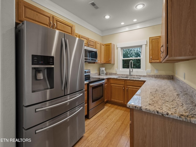 kitchen with sink, ornamental molding, light hardwood / wood-style floors, stainless steel appliances, and light stone countertops