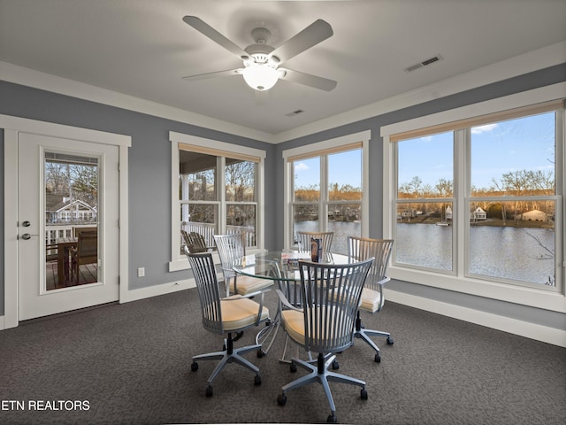 dining area featuring ornamental molding, dark colored carpet, ceiling fan, and a water view