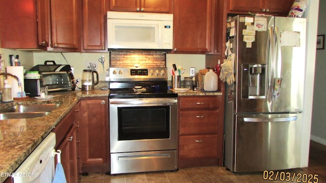 kitchen with tile patterned flooring, appliances with stainless steel finishes, stone countertops, and sink