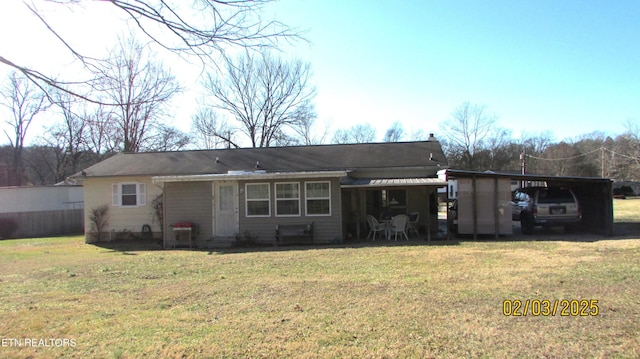 rear view of property featuring a lawn and a carport