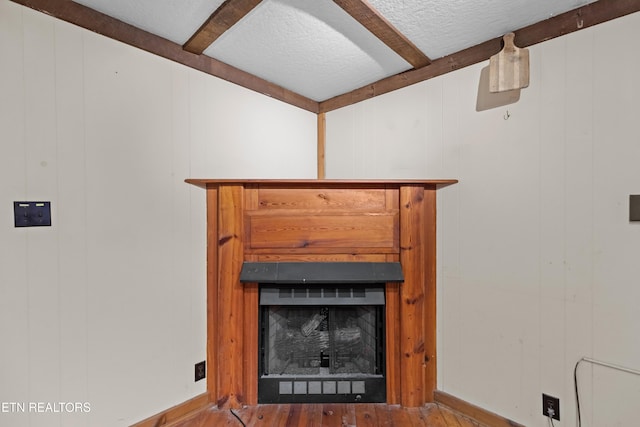 details with hardwood / wood-style floors, a textured ceiling, and beamed ceiling