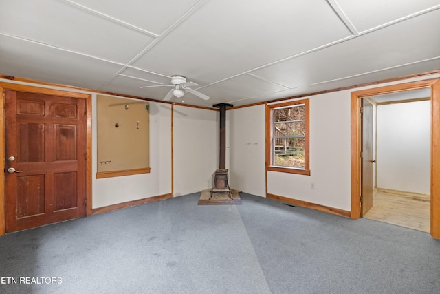 basement featuring carpet flooring, ceiling fan, and a wood stove