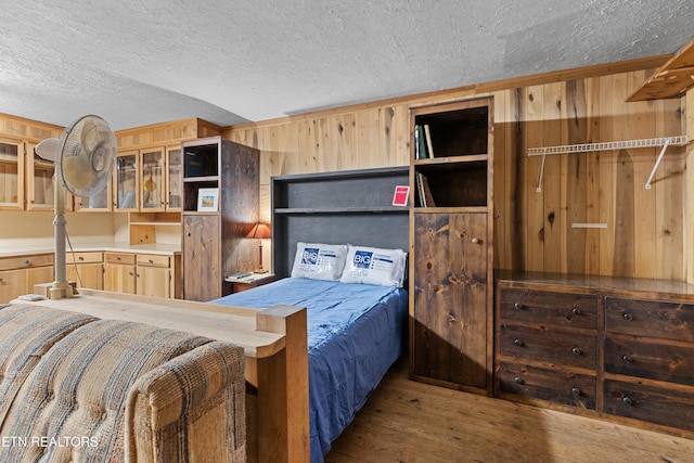 bedroom featuring hardwood / wood-style floors, wooden walls, and a textured ceiling