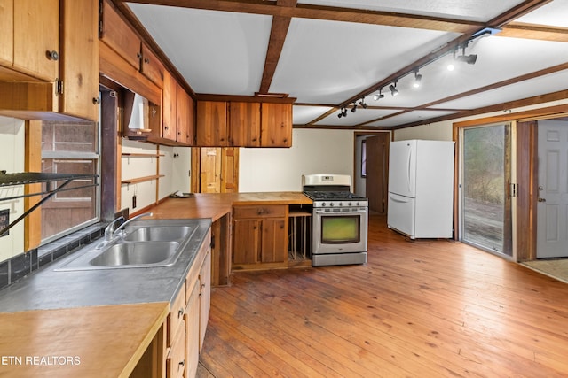 kitchen with sink, stainless steel gas stove, beam ceiling, white refrigerator, and light wood-type flooring