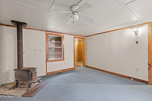 basement featuring ceiling fan, light carpet, and a wood stove