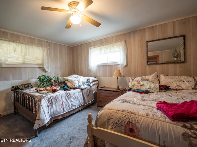 bedroom with dark colored carpet, ceiling fan, and wood walls