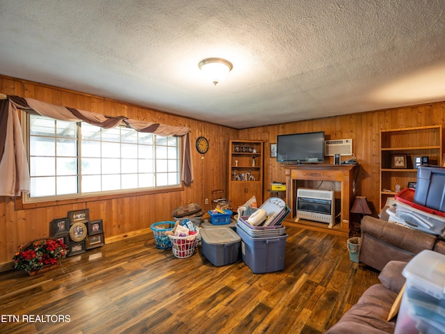 living room with dark wood-type flooring, heating unit, a textured ceiling, and wood walls