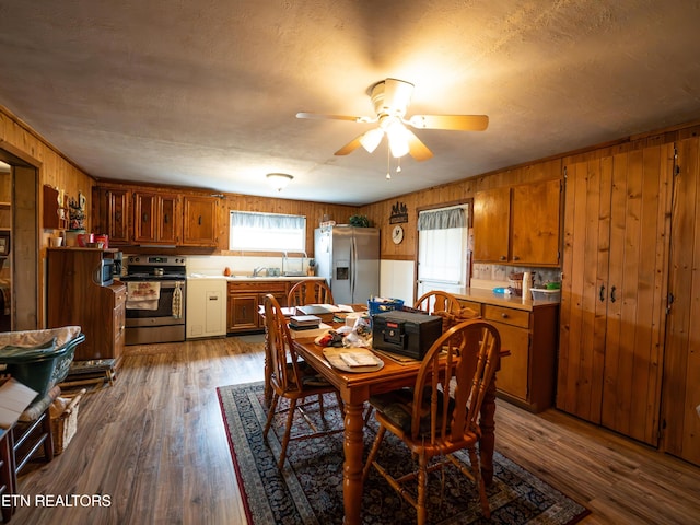 dining space featuring dark wood-type flooring, ceiling fan, wood walls, and a wealth of natural light