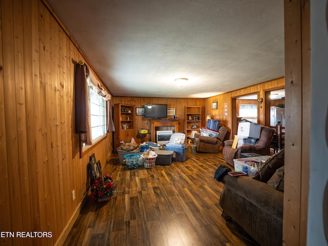 living room featuring dark hardwood / wood-style flooring, a textured ceiling, and wood walls