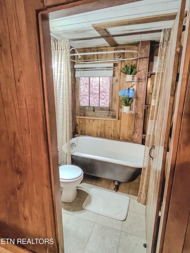 bathroom with toilet, a bath, and tile patterned flooring