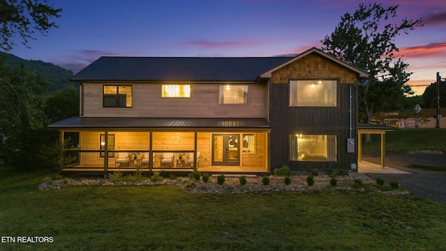 back house at dusk featuring a lawn