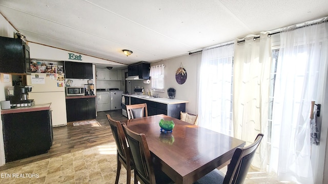 dining space featuring independent washer and dryer, lofted ceiling, sink, and a textured ceiling