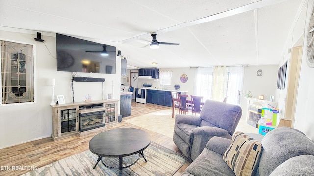 living room with ceiling fan, vaulted ceiling, and light wood-type flooring