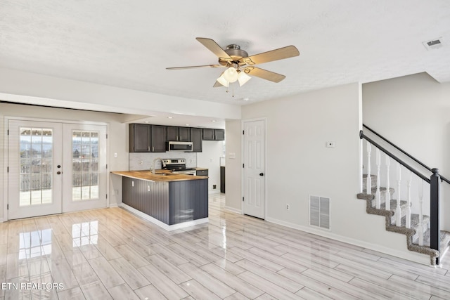 kitchen with butcher block counters, sink, ceiling fan, stainless steel appliances, and french doors