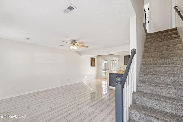 stairway featuring sink, french doors, and ceiling fan