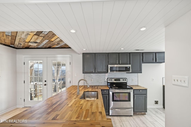 kitchen featuring french doors, butcher block counters, sink, appliances with stainless steel finishes, and decorative backsplash