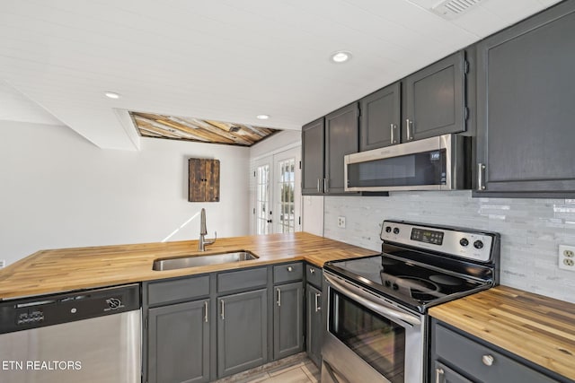 kitchen with butcher block countertops, sink, french doors, and appliances with stainless steel finishes