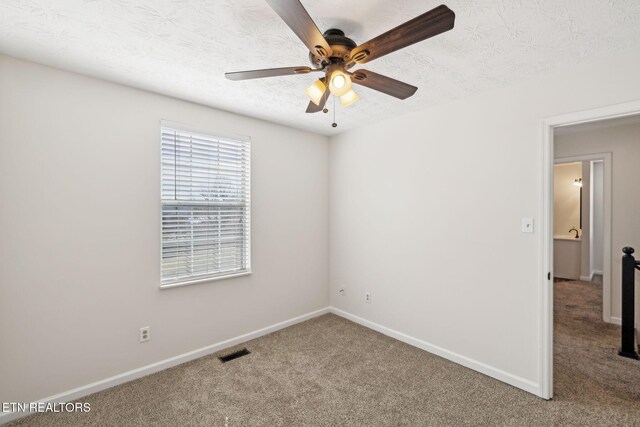 empty room featuring ceiling fan, carpet floors, and a textured ceiling