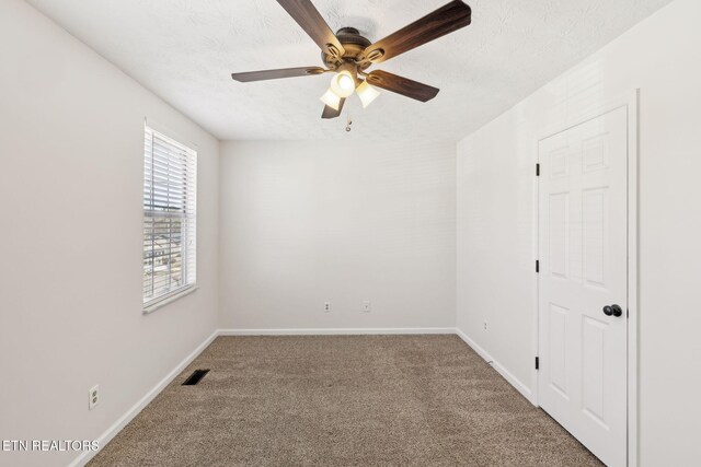 carpeted spare room featuring ceiling fan and a textured ceiling