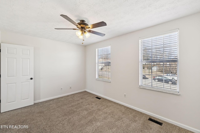 carpeted spare room with ceiling fan and a textured ceiling