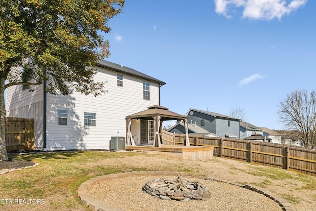 back of house with a gazebo, a yard, central AC, and a fire pit