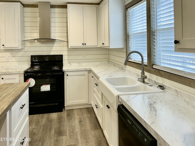 kitchen with black appliances, white cabinetry, and wall chimney exhaust hood