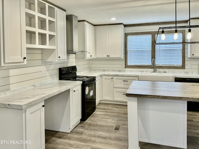 kitchen featuring sink, black appliances, pendant lighting, wall chimney range hood, and white cabinets