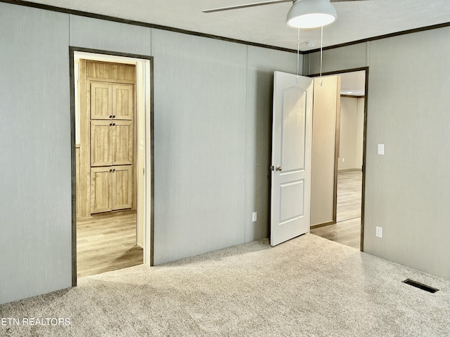 unfurnished bedroom with crown molding, connected bathroom, and light colored carpet