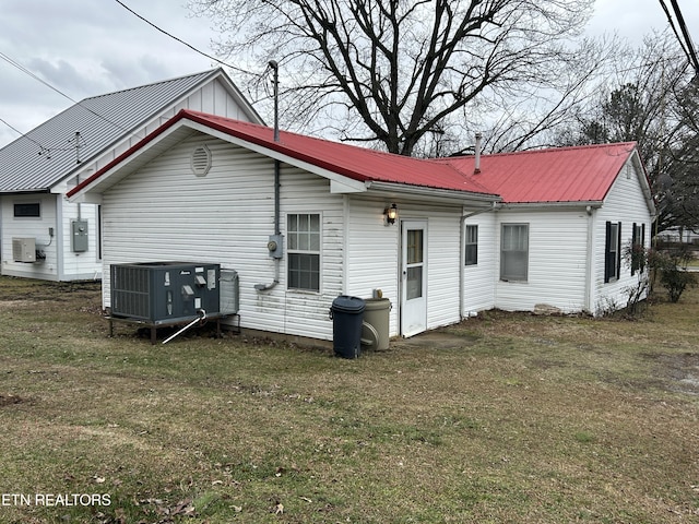 back of property with central AC unit and a yard