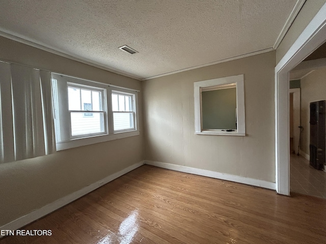 unfurnished room with hardwood / wood-style flooring, crown molding, and a textured ceiling