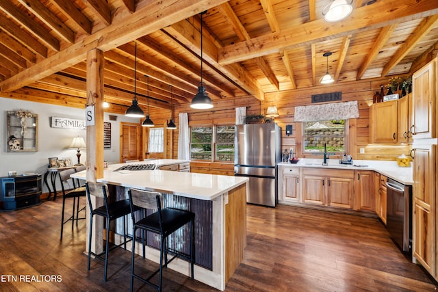 kitchen with a kitchen island, appliances with stainless steel finishes, decorative light fixtures, a breakfast bar area, and dark hardwood / wood-style flooring