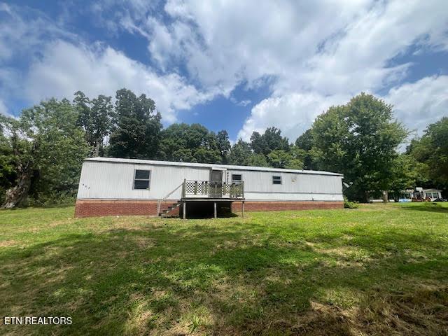 rear view of property with a yard and a deck