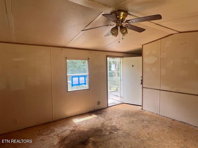 spare room featuring ceiling fan, lofted ceiling, and a textured ceiling