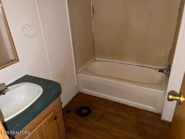 bathroom with hardwood / wood-style flooring, vanity, and a tub