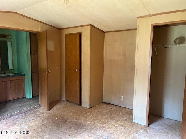 unfurnished bedroom featuring lofted ceiling and crown molding