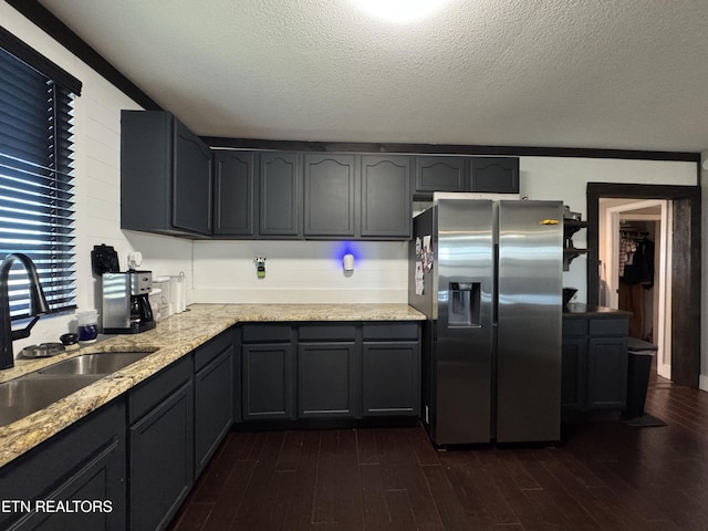 kitchen featuring dark hardwood / wood-style floors, stainless steel fridge, sink, and a textured ceiling