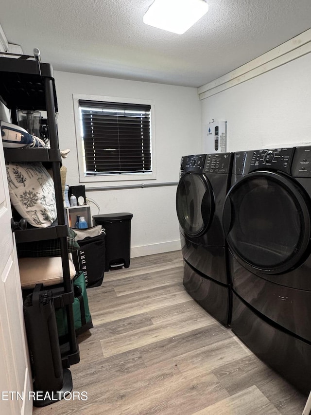 laundry room featuring separate washer and dryer, light hardwood / wood-style floors, and a textured ceiling