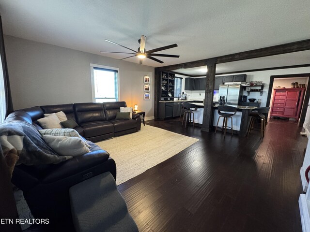 living room with ceiling fan, a textured ceiling, and dark hardwood / wood-style flooring