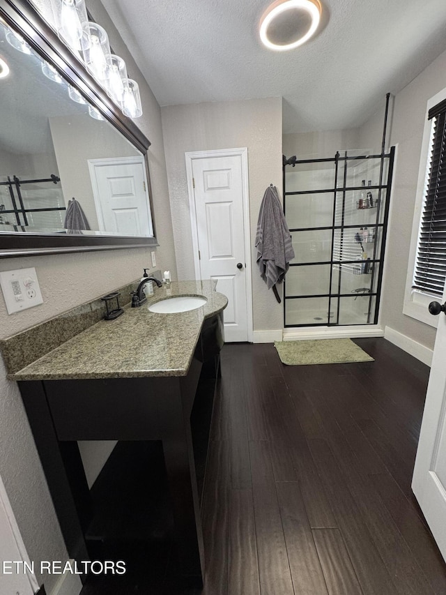 bathroom featuring walk in shower, vanity, hardwood / wood-style floors, and a textured ceiling