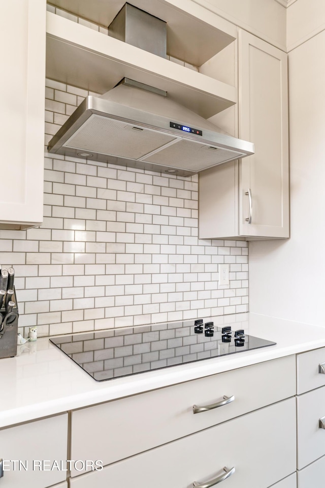 kitchen featuring ventilation hood, white cabinetry, black electric stovetop, and backsplash