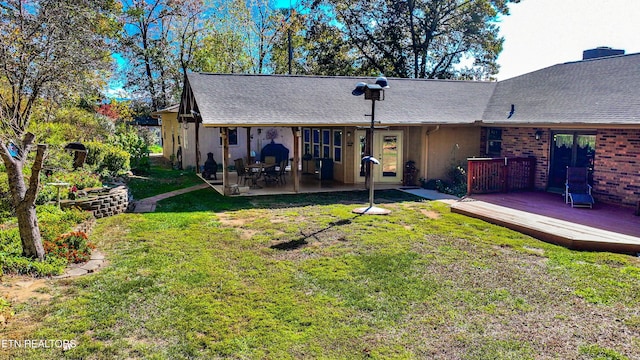 back of house featuring a yard, a shingled roof, and a wooden deck