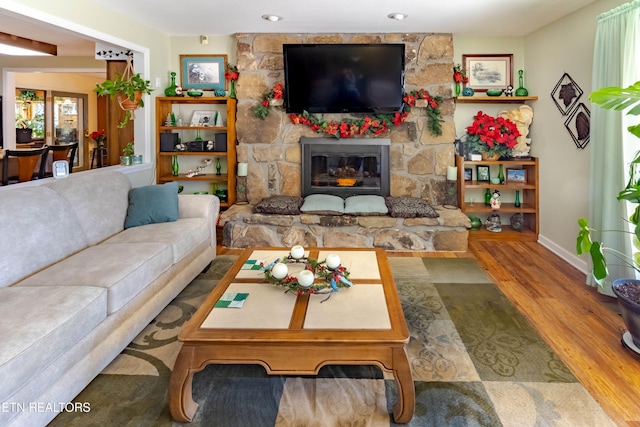 living room with a fireplace, baseboards, and wood finished floors