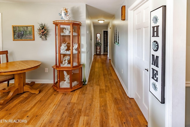 hall with light wood-type flooring and baseboards