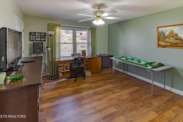 home office featuring a ceiling fan, baseboards, and wood finished floors