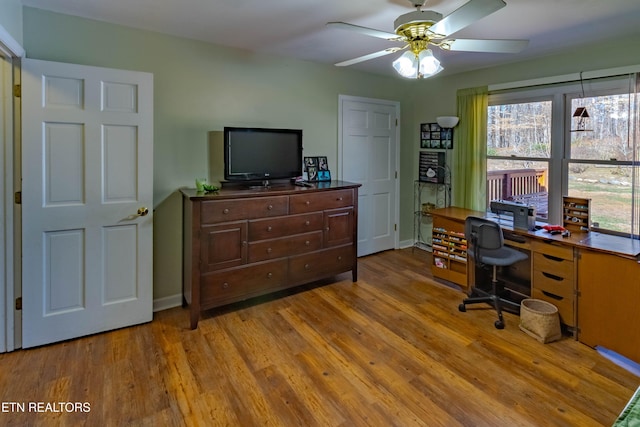 home office featuring light wood-type flooring, baseboards, and a ceiling fan