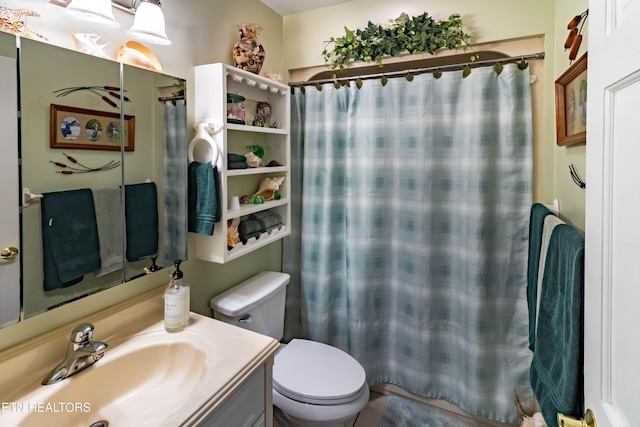 bathroom with curtained shower, vanity, and toilet