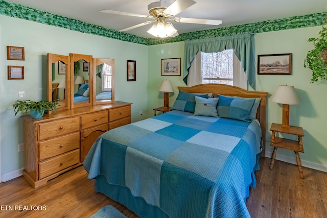 bedroom with ceiling fan, wood finished floors, and baseboards